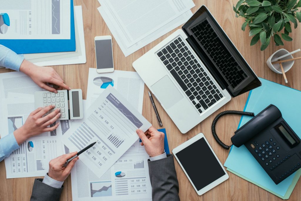 Overhead shot of people working at desk looking at data reports | Estate Planning Brisbane