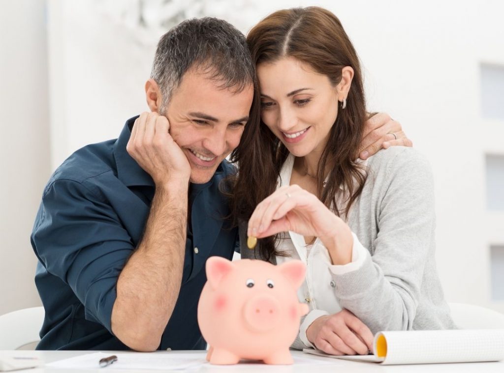 Couple looking at a piggy bank | | Featured image How much Money Do I Need to Retire Blog